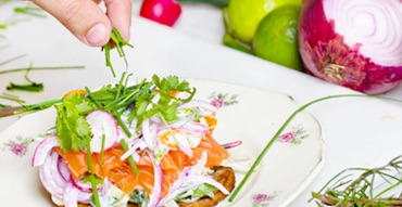 a dish of sliced salmon on a piece of bread, garnished with raddish and veggies