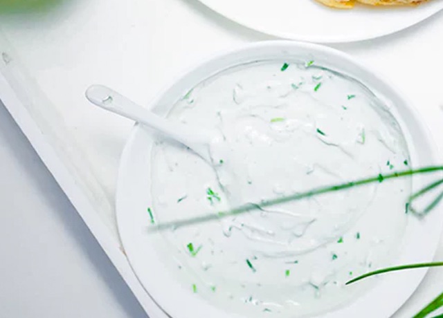 top down photo of spinach dip in a white bowl with a white spoon in it