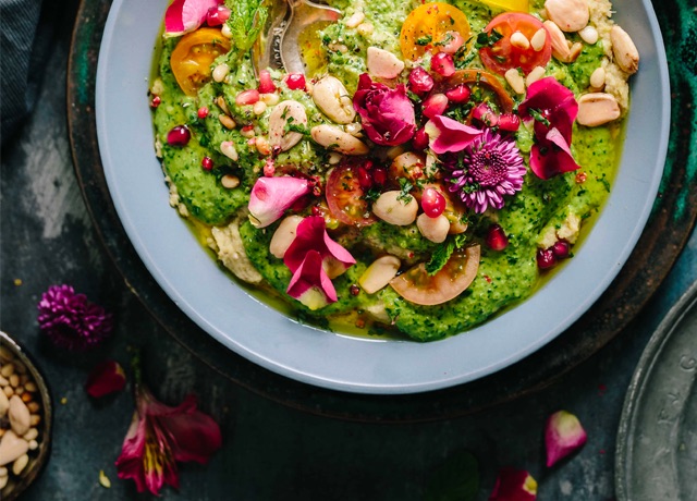 photo of a plate of guacamole ganished with tomatoes, nuts and flowers