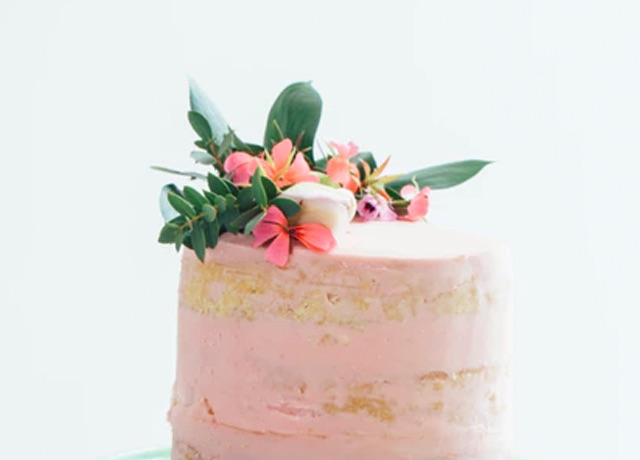 photo of a medium size stacked cake with pink icing. ganished with flowers